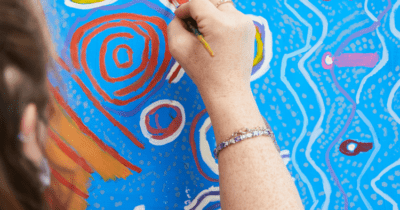 An artist painting on a blue canvas