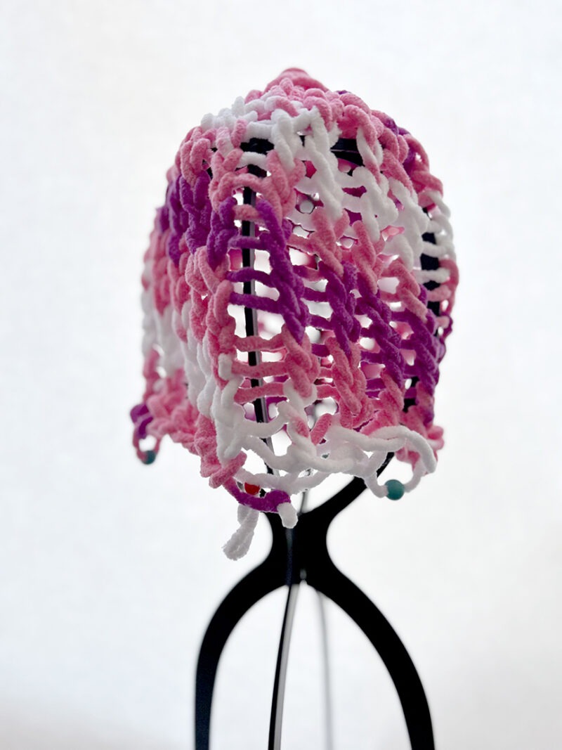 A pink, purple and white open weave taboggan hat.