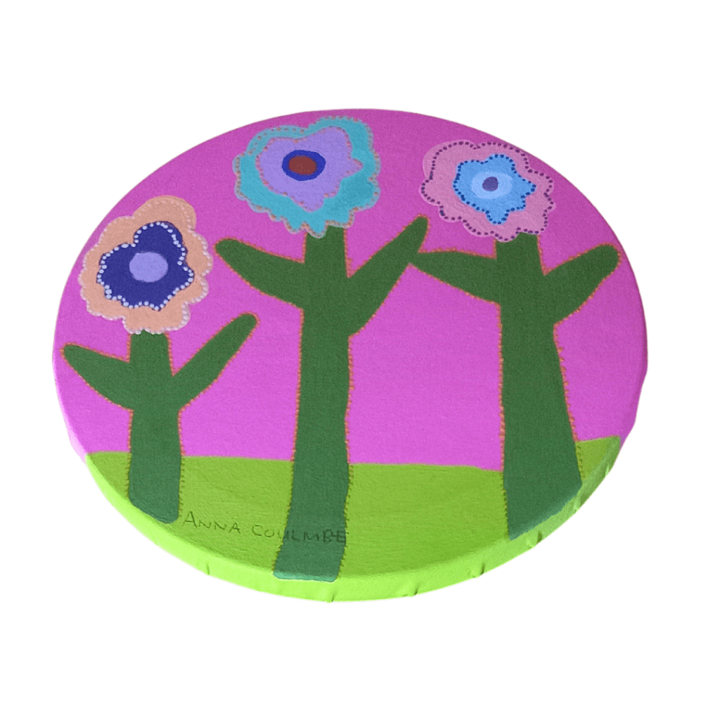 A small round acrylic painting of flowers in a meadow with a hot pink background.